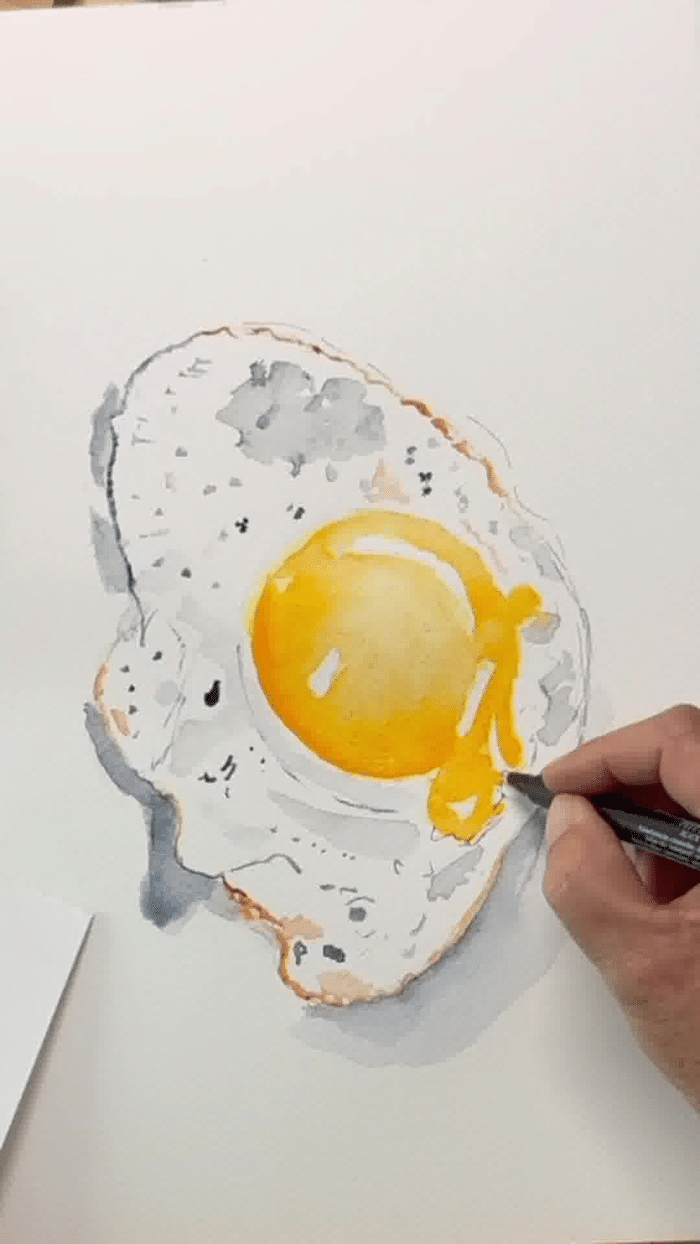 Étape avancée de l'aquarelle d'un œuf au plat, avec le blanc de l'œuf ombré en gris dilué